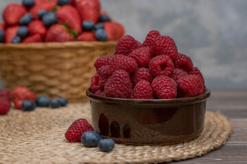 Strawberry and blueberry in basket and raspberries in bowl on wood table. Fresh berries.