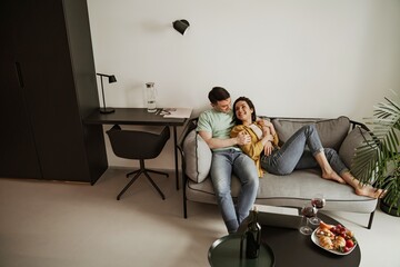 Lovely young couple showing romantic feeling to each other sitting on couch in living room. Happy family moving to new apartment