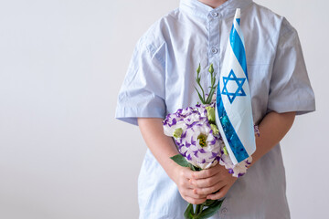 Child holding a bouquet of flowers and the flag of Israel on white background. Independence Day of...