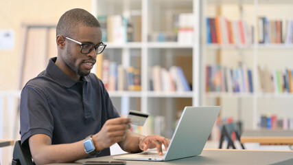 Fototapeta na wymiar Online Shopping by Young African Man on Laptop in Office