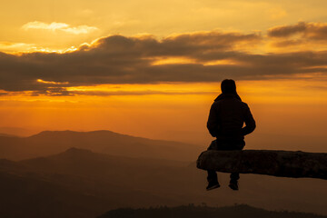 Man sit on the stone or rock cliff at "phu bak dai loei" at sunset or evening time.