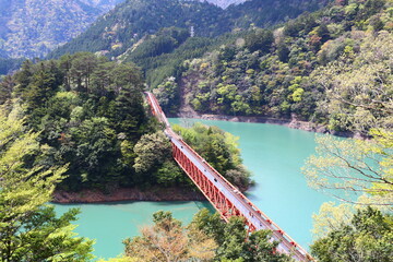 南アルプスの風景。湖上を走る鉄道。大井川鉄道奥大井湖上駅。大井川にある接岨湖（せっそこ）のかかる鉄橋、その途中に湖上駅がある。エメラルドグリーンの水に赤い鉄橋が映える。