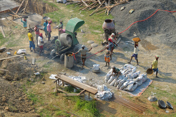 Top view of the Indian construction site. Indian people interfere with concrete, carry gravel and bags of cement. Asian builders are engaged in construction. India, Mayapur, March 16, 2019.