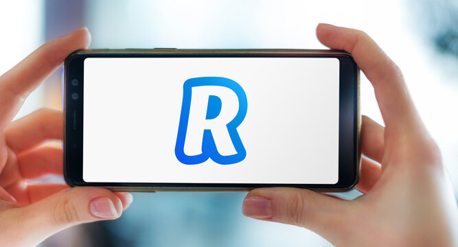 Hands Holding Smartphone Displaying Logo Of Revolut