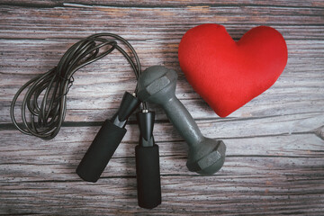 Jump rope, dumbbell and red heart  on the table