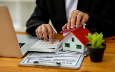 Close up wooden toy house with business woman signs a purchase contract or mortgage for a home, Real estate concept.	
