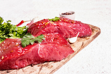 Raw beef steaks on a wooden cutting board