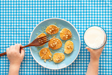 Miniature pancakes and milk glass on rustic background. Breakfast ideas for kids.