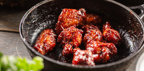 Spicy glazed marinated chicken wings in a dark pan