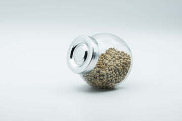 white pepper in glass bottle isolated on white background