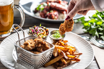 Crispy breaded chicken nuggets with french fries served on a plate with a dip and a salad