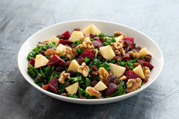 Kale salad with apple, beetroot, walnut and raisins in white plate. Healthy food