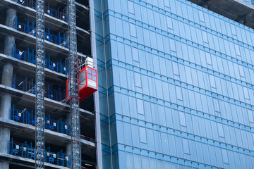 The construction elevator is going up. Glass skyscraper under construction with a construction...