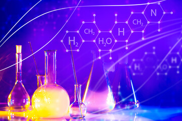 Laboratory glassware next to chemical elements. Chemical laboratory glassware with multi-colored liquid. Logos with chemical elements on a violet background. Test tubes in chemist laboratory