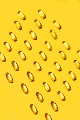 Yellow oval pills capsules vitamin Omega 3 over yellow