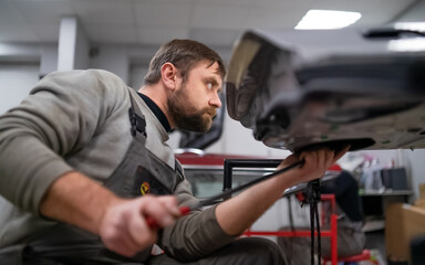 Bearded man's car repair service worker, hands photo in work repair process with a car door