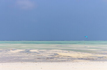 Kite surfing on tropical beach, low tide. Kite surfers on the sea. Scenic Indian Ocean with kite boards, Zanzibar, Paje beach. Active people concept. Summer recreation in Africa. Extreme sport concept
