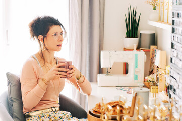 Jewelery creator drinking morning coffee in her working studio