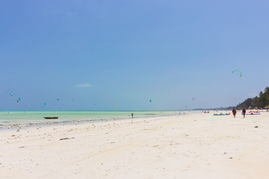 Kite surfing on tropical beach, low tide. Kite surfers on the sea. Scenic Indian Ocean with kite boards, Zanzibar, Paje beach. Active people concept. Summer recreation in Africa. Extreme sport concept