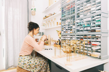 Jewelry designer working in studio, young woman creating handmade earrings