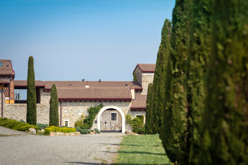 Fototapeta na wymiar Beautiful view of a country house with meadows and driveway with cypresses, blue sky in background. Spring in the countryside with nature all around. Outdoors, relax and cultural vacation concept.