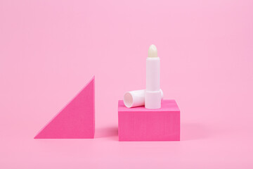 Close-up of white lip balm on a pink background. With geometric shapes.