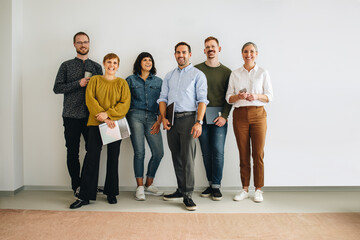 Successful creative team standing against wall