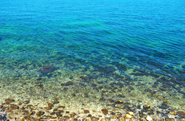 Naklejka na ściany i meble Coast with stones and blue ocean water, aerial view