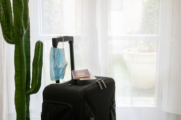 Fototapeta premium Luggage trolley bag ready to a new travel during covid-19 quarantine. Business travel flying with coronavirus protections. Passport boarding pass and medical mask. Safety travel, virus health concept