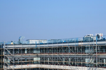 Scaffolding around an unfinished building under a clear sky.