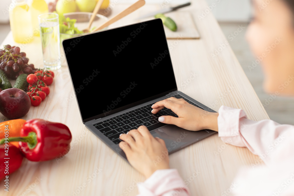 Poster Woman using pc with empty screen for mockup in kitchen
