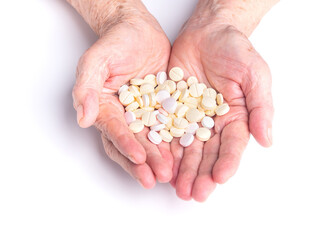 Pills on the palm of a senior woman with a white background. Close-up photo. Aged people and healthcare concept