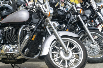 Naklejka premium Motorcycles parked on the motorcycles parking lot. Closeup of motorcycles front wheel.