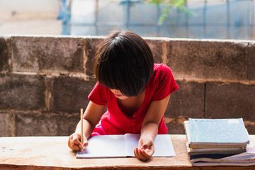 A girl sitting on a wooder table doing homework
