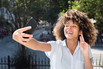 Happy young black woman taking selfie portrait with mobile phone