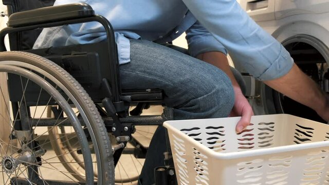 Impaired man in wheelchair put laundry in washing machine