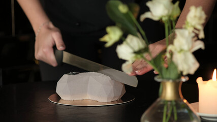 Obraz na płótnie Canvas A man cuts a heart-shaped cake with a big knife during a celebration