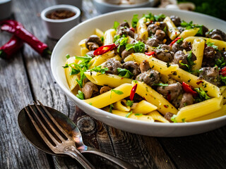 Penne with mushrooms in cream sauce on wooden table
