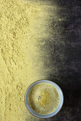Tea matcha in bowl and scattered dry match tea powder on a black background