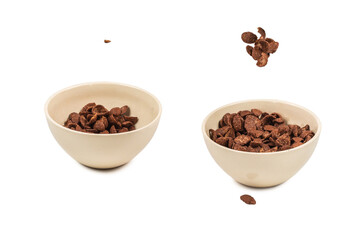 Chocolate corn flakes falling to the white bowl isolated on white. Motion.