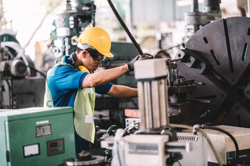 Work at factory.Asian worker man  working in safety work wear with yellow helmet and glasses l ear muff using equipment.male mechanical asia in factory workshop industry machine professional