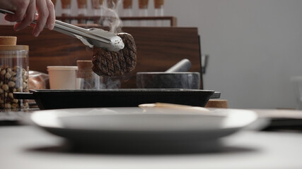 man hand use tongs to pick up beef steak from grill pan