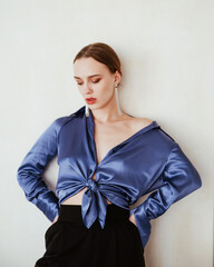 Trendy sexy girl portrait thinking in a blue silk  blouse and black pants in stylish modern clothes in white background isolated posing. Fashion style
