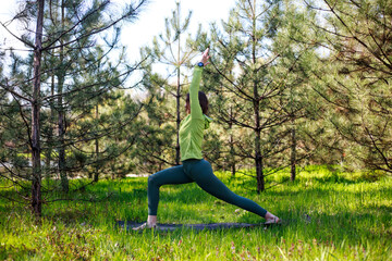 Girl doing yoga in fir park, fitness exercise outdoors, healthy lifestyle and freshness of pure nature