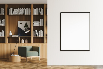 Bright modern living room interior furnished by green armchair, bookshelf and lamp. Mock up poster frame on white wall.Copy space. Wooden floor. Home library.
