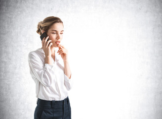 Businesswoman talking with phone in hand, mockup empty wall