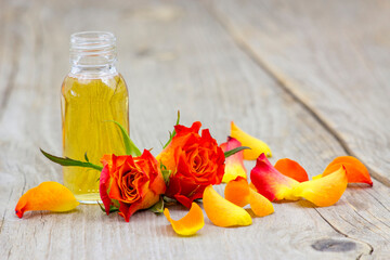bath oil and orange roses on old wooden background