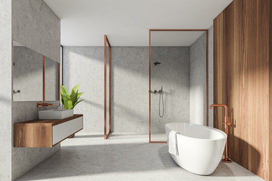 Modern Bathroom interior in new luxury home. Stylish hotel room. Open space area. Concrete wooden walls and floor. Bathtub and Shower cabin.