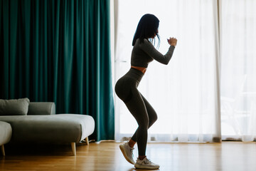 Athletic woman sports workout at home. Home workout. Slim female wearing sports wear stretching at home and weight loss workout in a living room.