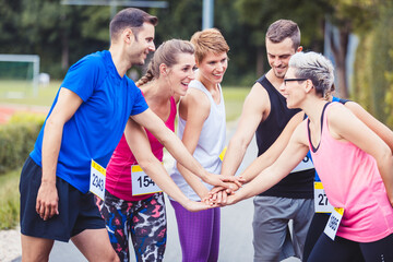 Group of marathon runners stacking hands
